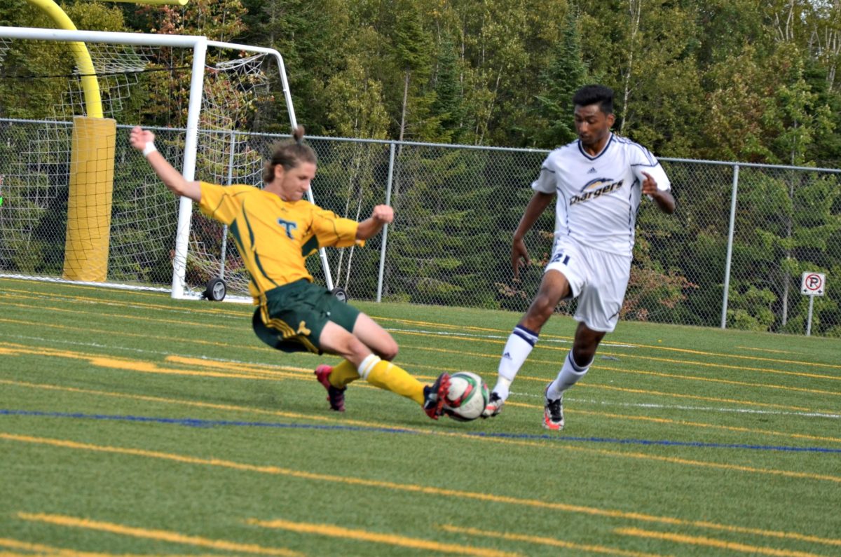 St. Thomas Tommies wing back Oliver Dussault, left, and Crandall Chargers midfielder Ryan Alli battle in ACAA men's soccer action Saturday at Scotiabank Park South. Photo: Nathan DeLong/The Aquinian 