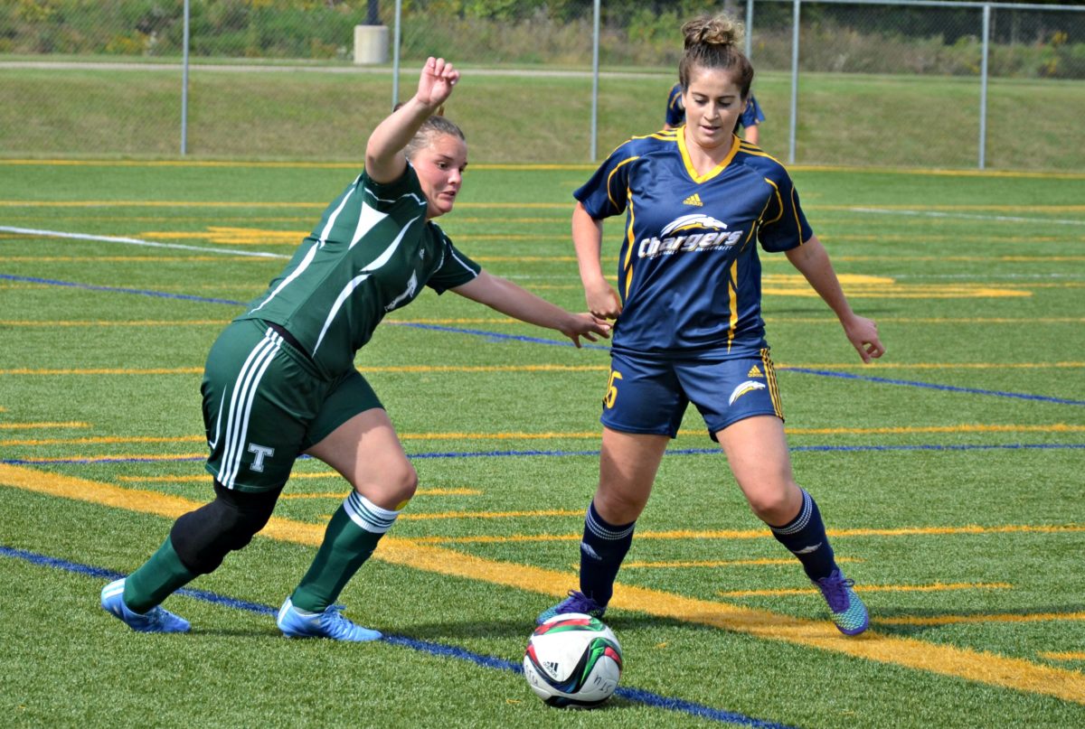 St. Thomas Tommies centre back Vanessa Pettersson, left, and Crandall Chargers midfielder Madison McHatten chase the ball during ACAA women's soccer action Saturday at Scotiabank Park South. Photo: Nathan DeLong/The Aquinian