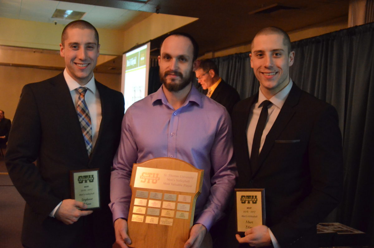 Stephane Blinn, left, and Marc Blinn, right, accept the men's volleyball Most Valuable Player award from head coach Francis Duguay. Photo: Nathan DeLong/The AQ 